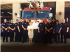 Older Photo of Firefighters with a Woman Holding a Bouquet of Flowers