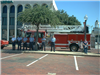 Firefighters Standing in Front of a Fire Truck on a Business Street