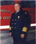 Fireman in Uniform Standing in Front of a Fire Truck Smiling